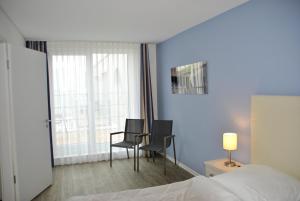 Habitación de hotel con cama, sillas y ventana en Apartmenthaus Hafenspitze Ap 42 "Segler", mit Sauna, Blickrichtung offene See - a72332, en Eckernförde