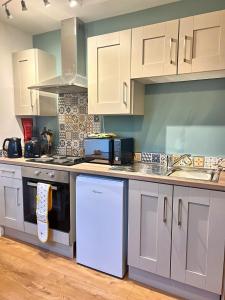 cocina con armarios blancos y fogones en Bangor Central Apartments en Bangor