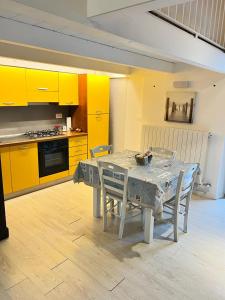 cocina con mesa con sillas y armarios amarillos en La dimora sul porto en Termoli