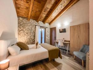 a bedroom with a bed in a room with a stone wall at El Forn de Freixenet con servicios de un hotel in Lleida