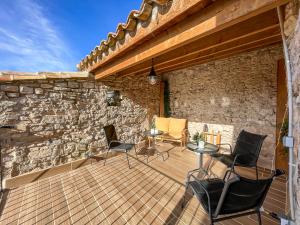 a patio with chairs and a table and a stone wall at El Forn de Freixenet con servicios de un hotel in Lleida