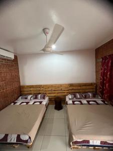 two beds in a room with a ceiling fan at Ujud Sepakat Homestay in Melaka