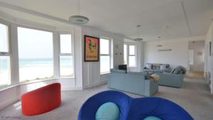 a living room with a couch and chairs and windows at Chycaron, Riviere Towans in Hayle
