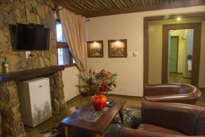 a living room with a table and a stone wall at Emoya Basotho Lodge in Bloemfontein