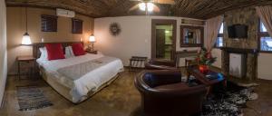 a bedroom with a bed and a living room with a couch at Emoya Basotho Lodge in Bloemfontein