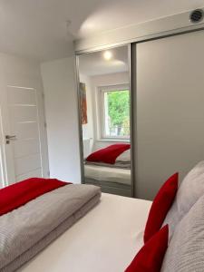 1 dormitorio con cama con almohadas rojas y espejo en Mieszkanie w Dobrzeniu Wielkim, en Dobrzeń Wielki
