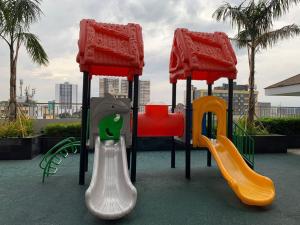 a playground with two slides and a swing set at Cosy Luxy Coast Residences Staycation in Manila