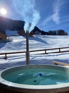 ナンダにあるSki in out Swiss Alps Chalet Charelle by Jolidiのスチームが出る雪の中のホットタブ