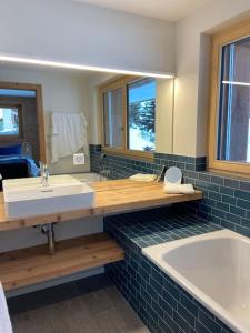 a bathroom with a sink and a tub and a mirror at Ski in out Swiss Alps Chalet Charelle by Jolidi in Nendaz