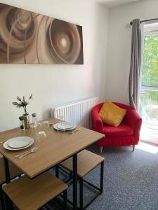 een eetkamer met een tafel en een rode stoel bij Lovely 2 bedroom flat in greater london in Londen