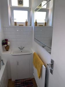een witte badkamer met een wastafel en een spiegel bij Lovely 2 bedroom flat in greater london in Londen