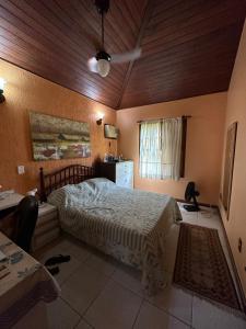 a bedroom with a bed and a desk and a window at Casa da Ogiva in Cabo Frio