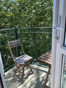 een houten stoel op een veranda naast een hek bij Lovely 2 bedroom flat in greater london in Londen