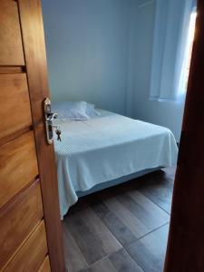 a bedroom with a bed with white sheets and a door at Casa Silvano's II in Foz do Iguaçu