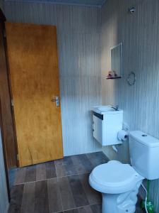 a bathroom with a toilet and a wooden door at Casa Silvano's II in Foz do Iguaçu