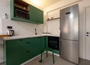 een keuken met groene kasten en een roestvrijstalen koelkast bij Boutique Central old town Apartment in Beer Sheva
