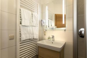 Baño blanco con lavabo y espejo en Pension Bernhardhof, en Otterfing