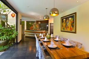 a dining room with a long wooden table and chairs at Elok Villas in Seminyak