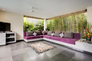 a purple couch in a living room with a large window at Elok Villas in Seminyak