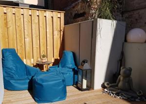 un patio con sillas azules, una mesa y una valla en Willem und Konsorten - Ankerbucht, en Heiligenhafen