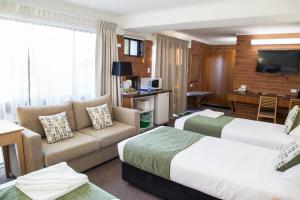 ein Hotelzimmer mit 2 Betten und einem Sofa in der Unterkunft Murwillumbah Motor Inn in Murwillumbah