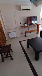 ein Wohnzimmer mit einem Sofa, einem Tisch und einem TV in der Unterkunft Vistalba House in Ciudad Lujan de Cuyo