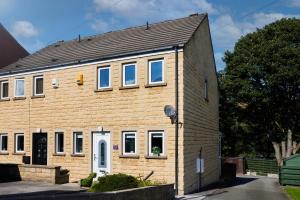 a brown brick house with a black roof at Links to M62 - 3 bedroom property in Golcar