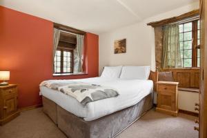 a bedroom with orange walls and a large bed at The Mountain Cottages - Pelton Wheel in Coniston