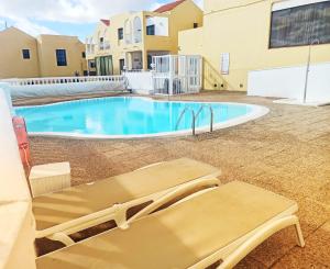 uma piscina com duas cadeiras ao lado de um edifício em Caleta Paraiso 127 em Costa de Antigua