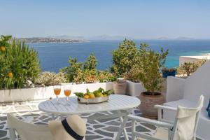 einen Tisch mit einer Schale Obst und zwei Gläsern Wein in der Unterkunft Spetses Sea View Luxury House in Spetses