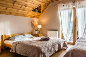 a bedroom with two beds and a wooden ceiling at Willa Golasówka in Muszyna