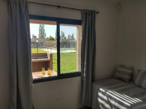 Zimmer mit einem Fenster, einem Bett und einem Tisch in der Unterkunft Buenas Tierras Cabañas in San Rafael + 36 Fotos
