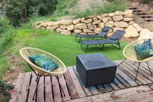 3 sillas y TV en una terraza de madera en Cottage romantique, son jacuzzi privatif, piscine en Rillieux