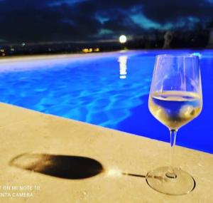una copa de vino sentada en una mesa junto a una piscina en Cottage romantique, son jacuzzi privatif, piscine en Rillieux