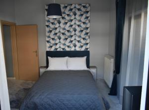ein Schlafzimmer mit einem Bett mit einer blauen Decke und einer Wand in der Unterkunft Meteora House with a view in Kalambaka