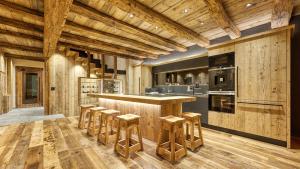 a kitchen with wooden floors and a bar with stools at Akchalet Akon in Livigno