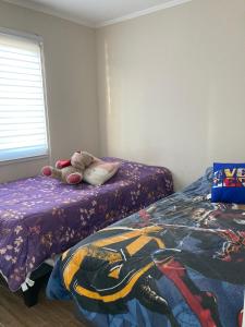um bicho de peluche sentado numa cama num quarto em Senderos em Coquimbo