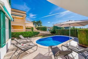 uma villa com uma piscina, cadeiras e um guarda-sol em Ideal Property Mallorca - Casa Osborne em Port d'Alcudia