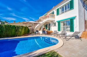 uma piscina em frente a uma casa com cadeiras e um guarda-sol em Ideal Property Mallorca - Casa Osborne em Port d'Alcudia