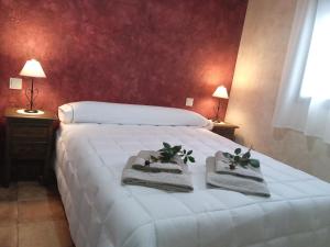 a bedroom with a white bed with towels and plants on it at El capricho de Diego in La Puebla de Montalbán