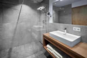 La salle de bains est pourvue d'un lavabo et d'une douche. dans l'établissement Alpin Residenzen Buchensteinwand St. Ulrich by Alpina-Holiday, à Sankt Ulrich am Pillersee