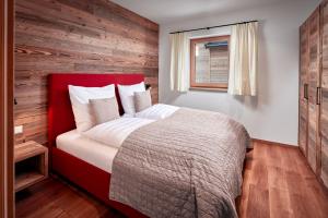 um quarto com uma cama vermelha e uma parede de madeira em Alpin Residenzen Buchensteinwand St. Ulrich by Alpina-Holiday em Sankt Ulrich am Pillersee