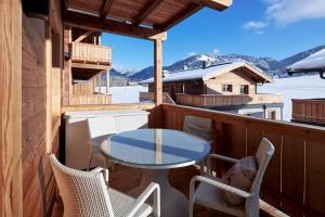 patio con mesa y sillas en el balcón en Alpin Residenzen Buchensteinwand St. Ulrich by Alpina-Holiday, en Sankt Ulrich am Pillersee