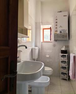 La salle de bains blanche est pourvue d'un lavabo et de toilettes. dans l'établissement Casa dei MoMi, à Piombino