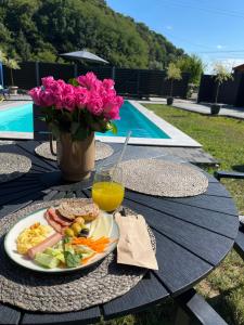 einen Tisch mit einem Teller Essen, einem Getränk und Blumen in der Unterkunft Sandal in Shayan