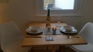 a wooden table with a bottle of wine and glasses at The Picture House Stylish Apartment in Fowey in Fowey