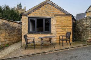 a table and chairs in front of a building at Chic Cotswold Tiny Home - Oddity House in Blockley