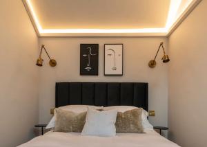 a bedroom with a bed with a black headboard and lights at Chic Cotswold Tiny Home - Oddity House in Blockley