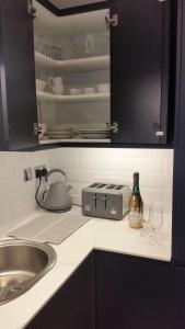 a kitchen counter with a sink and a toaster and glasses at The Picture House Stylish Apartment in Fowey in Fowey +15 photos