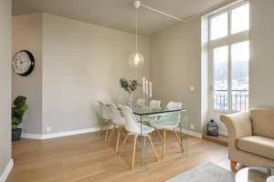 uma sala de jantar com uma mesa de vidro e cadeiras brancas em Elegant Bergen City Center Apartment - Ideal for business or leisure travelers em Bergen